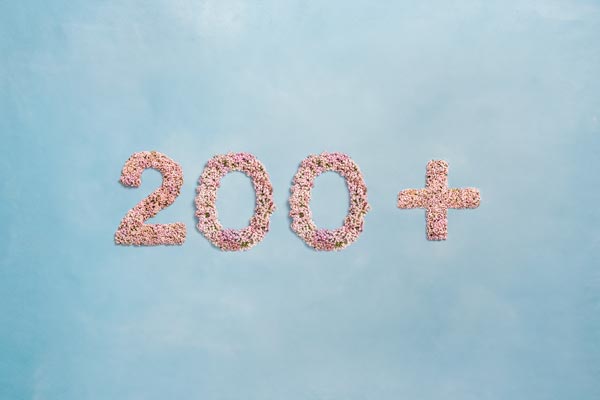 Tallet 200+, skrevet med lyserøde blomster på lyseblå baggrund